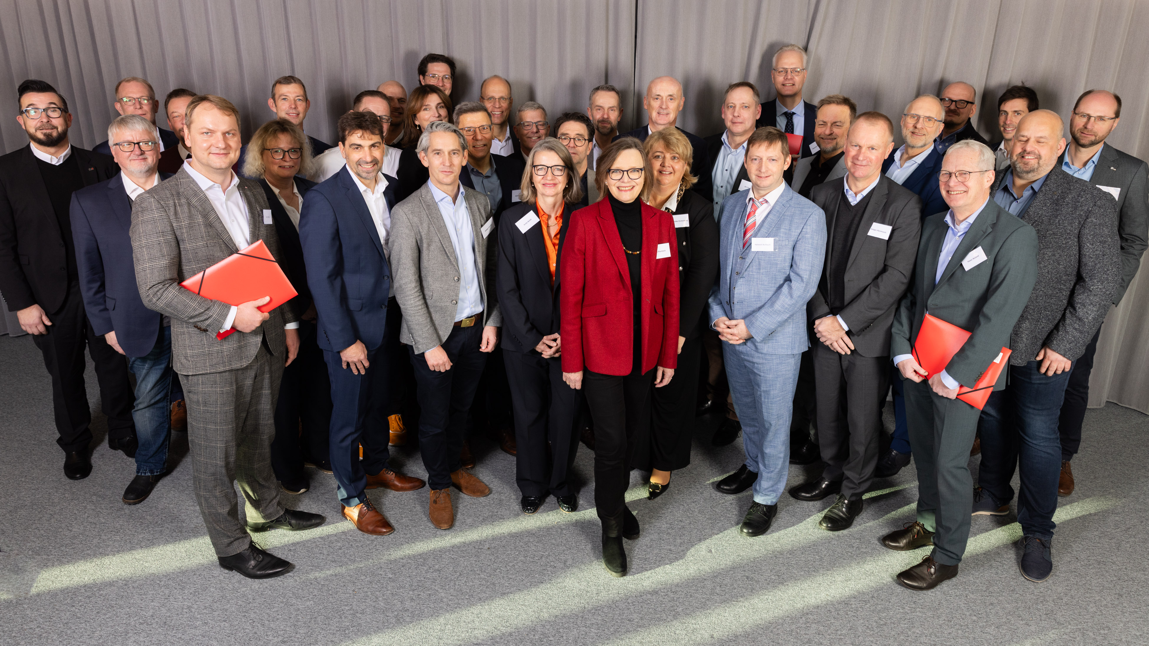 Eine Gruppe von Menschen posiert vor einem grauen Vorhang.